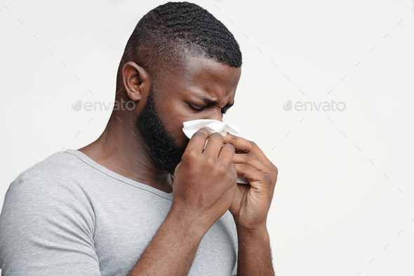 Guy having runny nose, touching his nose with napkin