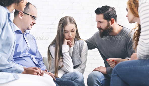 Patients comforting depressed woman at therapy session