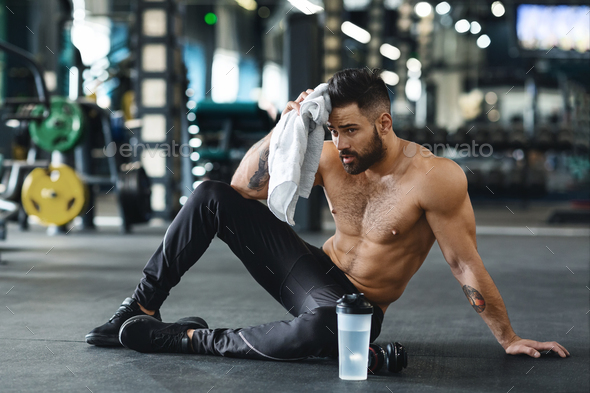 Handsome athlete wiping sweat after workout at gym