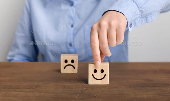 Hand of a businessman chooses a smiley face on wood block cube - Stock Photo - Images