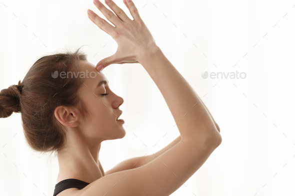 Woman doing namaste gesture, hands to forehead
