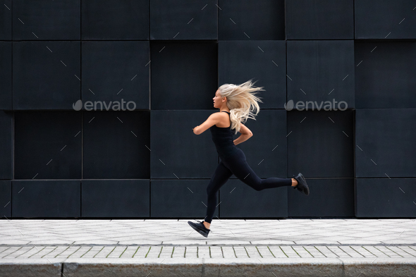 Fit young woman running in minimalist urban city environment - Stock Photo - Images