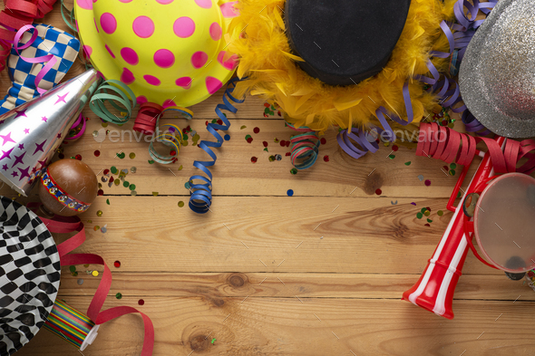 Carnival background on a wooden surface. Masks, hats, coiled streamers,  confetti and many more Stock Photo by Nick_Paschalis
