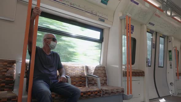 senior adult ride alone on a train with mask during day covid pandemic