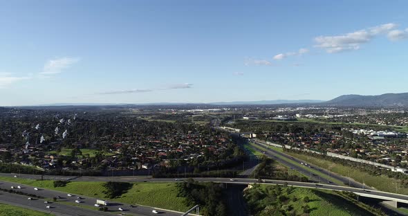 Slow smooth tracking perspective peeling back to reveal highway interchange below as flock of birds alt