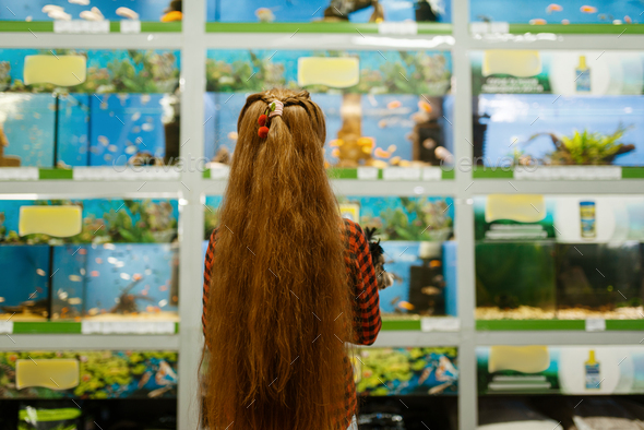 Girl looking on fishes in aquarium, pet store - Stock Photo - Images