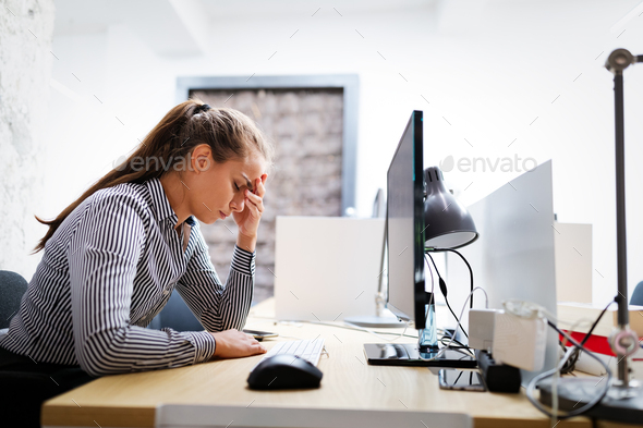Overworked and frustrated young woman in front of computer in office