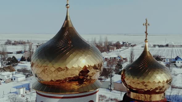 Golden Domes of an Orthodox Church in the Village in Winter Snowy Weather