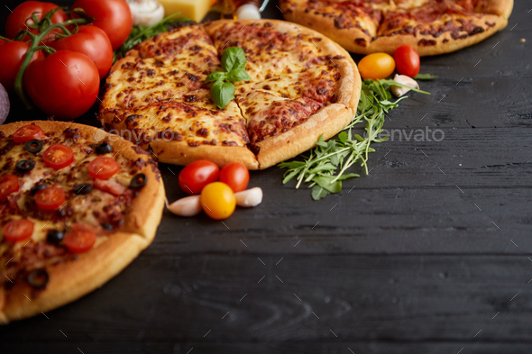 Freshly served, three various pizzas placed among tasty ingredients. Top view - Stock Photo - Images