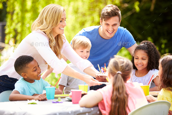 Parents And Son Celebrating Birthday With Friends Having Party In Garden At Home