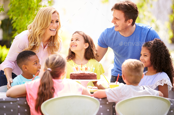 Parents And Daughter Celebrating Birthday With Friends Having Party In Garden At Home