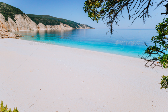 Amazing Fteri beach lagoon, Kefalonia, Greece. Tourists under umbrella chill relax near clear blue - Stock Photo - Images