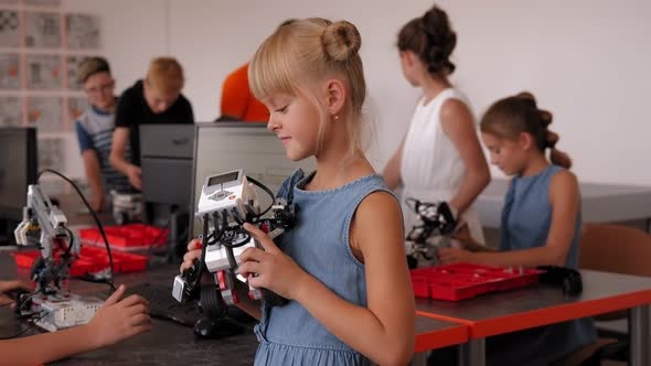 A Student Holds a Work Assembled From Plastic Parts in a Robotics Lesson alt