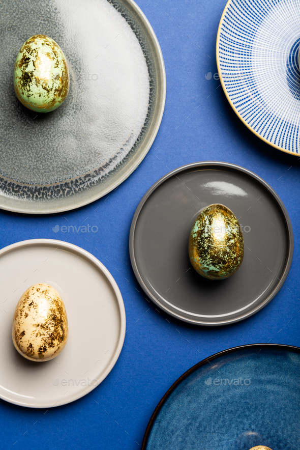 Different Plates with Easter Eggs of pastel colors on blue background - Stock Photo - Images