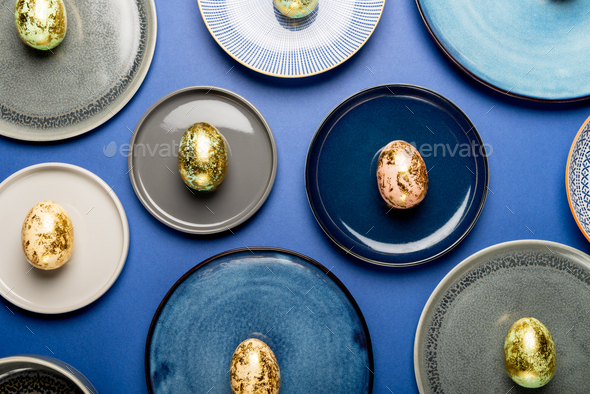 Different Plates with Easter Eggs of pastel colors on blue background - Stock Photo - Images
