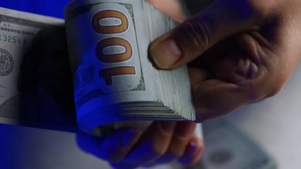 Hands Counting US Dollar Bills or Paying in Cash Against the Backdrop of Police Car Lights alt