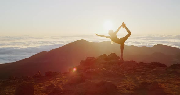 Woman performing yoga pose at sunrise