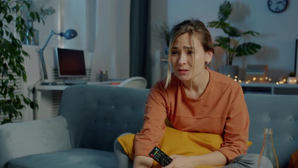 Attractive Young Lady Watching Drama on TV Expressing Empathy Sitting on Couch in Dark House alt
