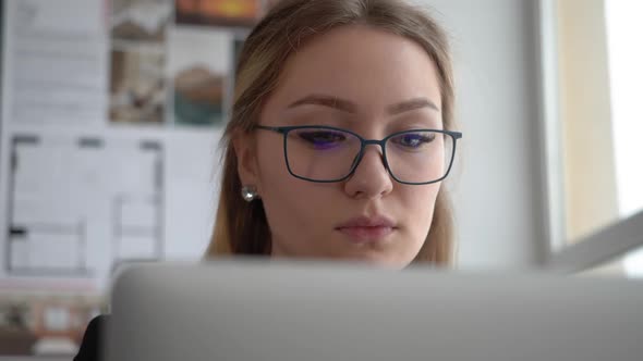 Beautiful Woman Engineer in Glasses Works on Laptop Computer in Creative Office alt