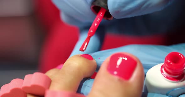 Manicurist Applies Red Polish to Client Toenails