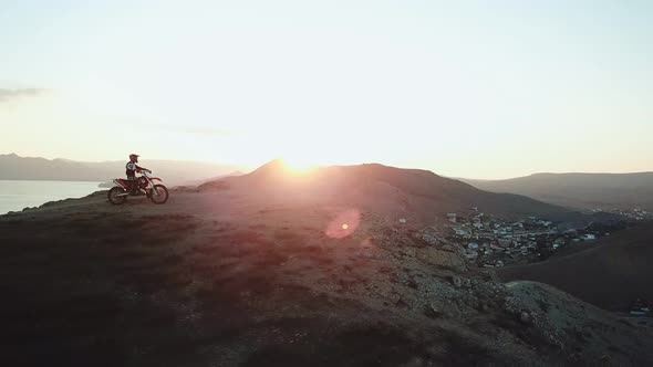 Drone View of Man on Motorbike Extremely Rides Across the Hills with Black Sea on Background in