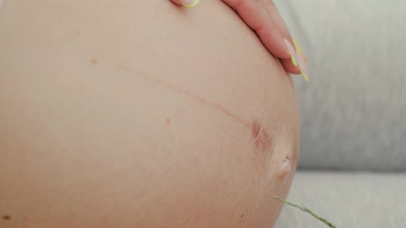 Pregnant woman gently strokes belly with hand.Close up.