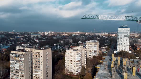 Under construction high-rise building with yellow construction crane with dramatic sky
