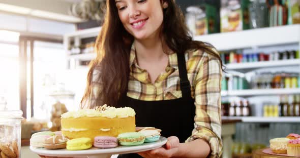 Waitress holding dessert on cake stand in cafe alt