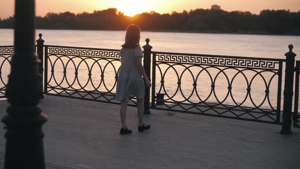 the Girl Came to the Embankment of the River and Looks at the Sunset