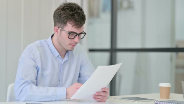 Young Man Reading Documents in Office alt