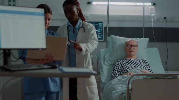 Nurse and African American Medic Looking on Laptop in Hospital Ward alt