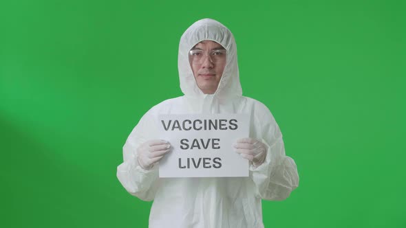 Asian Man Wear Uniform Ppe And Holding Vaccines Save Lives Sign In The Green Screen Studio alt