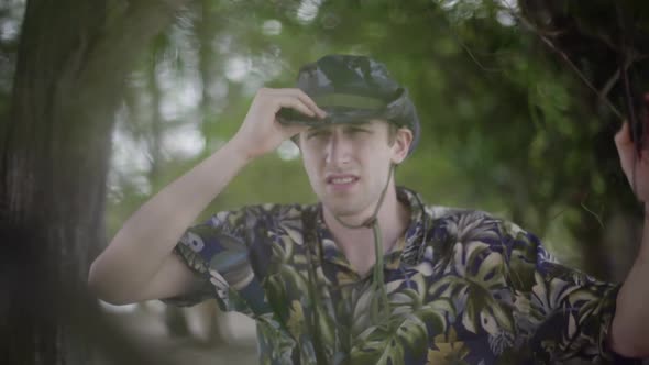 Young white man explores tropical jungle. Wearing Tilly hat and Hawaiian shirt. Scans the horizon wi alt