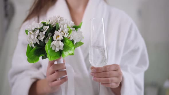 Closeup Bridal Bouquet and Champagne Glass in Slim Female Caucasian Hands alt