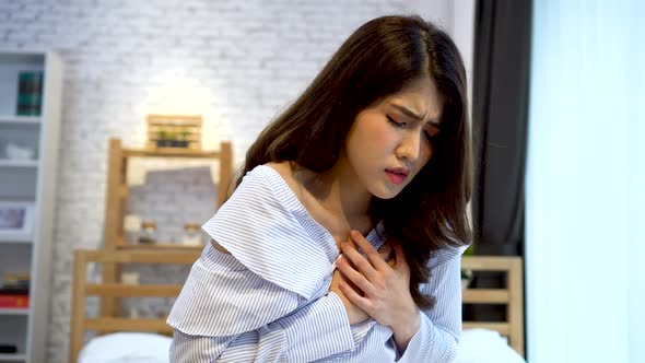 Young Asian Woman Having Shortness of Breath Asthma Difficult to Breathe Problems on Bed at Home alt