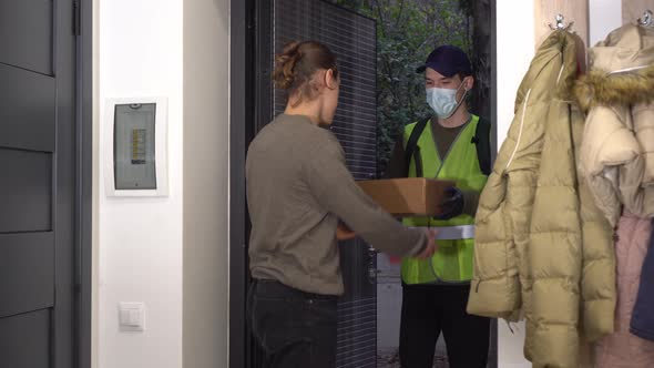 A courier in a medical mask delivered a package of food to the customer's home before the door alt