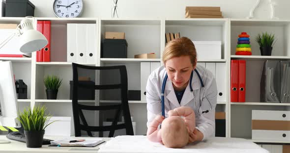 Doctor Makes Gymnastic Exercises with Child in Office