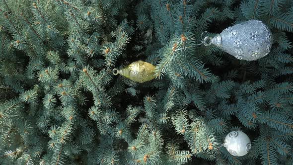 There are toys hanging on the Christmas tree. Vertical