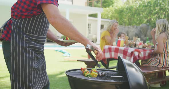 Happy caucasian family having barbecue and eating in garden alt