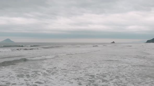 Lateral drone footage of the beach, cloudy day, waves, agitaded sea, landscape of Juquehy, Ubatuba, alt