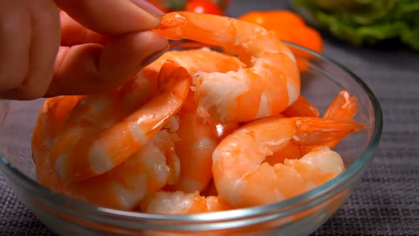 Hand Puts One Peeled Shrimp in a Glass Bowl alt