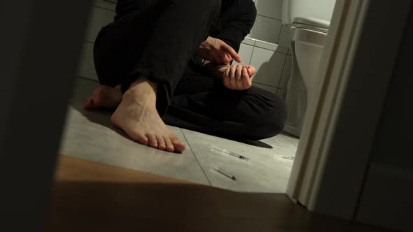 Drug Addict Sits On Floor In Toilet And Takes Injection In His Hand