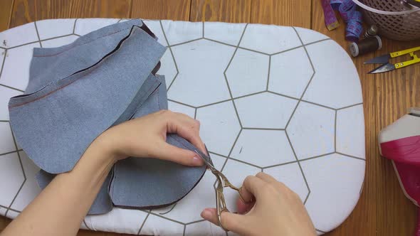 Women's Hands Cut Off Corner of Fabric with Scissors