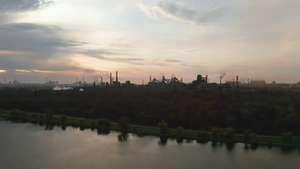 Aerial View. Pipes Throwing Smoke in the Sky. Large Plant on the Background of the City.