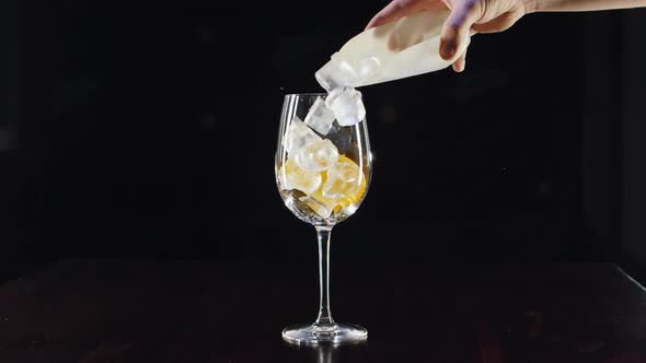 Close Up Bartenders Hands Pouring Prosecco in Wine Glass with Ice, Mixing Cocktail with Orange Juice