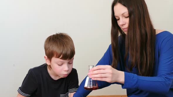 Chemical Reaction with Gas Emission in Flask with Red Liquid. Mom and Son Doing Chemistry.
