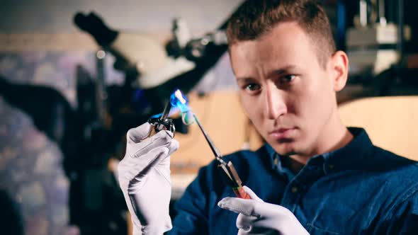 Male Silversmith Is Burning the Frame of the Silver Ring. Jeweler Makes a Piece of Jewelry alt