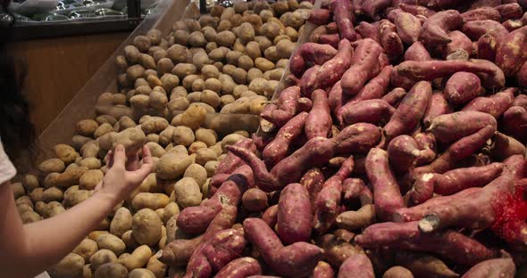 Young Woman in the Grocery Section of a Supermarket Picks Up a Bag of Potatoes to Be Weighed on a alt