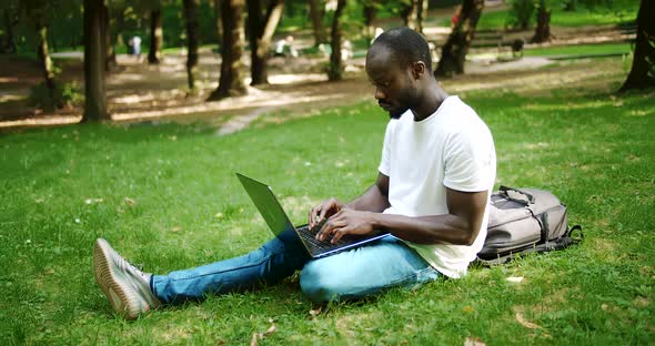 Afro-american Student Typing on Laptop in Park