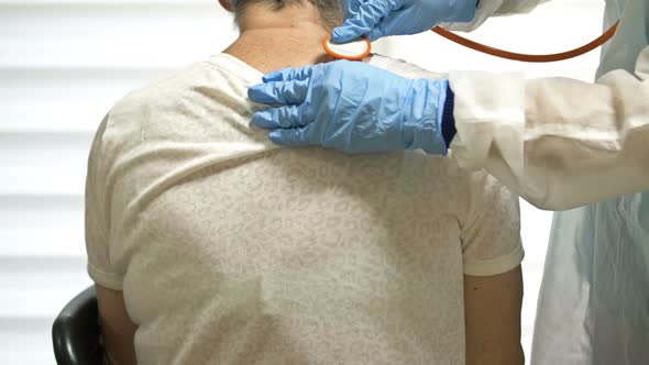 Female Doctor Listens with a Phonendoscope to an Elderly Patient with Symptoms of Coronavirus alt